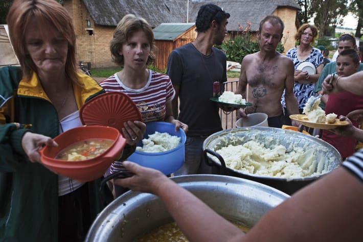 Vecinos de un suburbio de blancos pobres en Sudáfrica hacen cola para recibir comida de la beneficencia, en Krugersdorp, marzo de 2010. Se estima que un total de 450,000 sudafricanos blancos, de entre 4.5 millones de blancos que habitan Sudáfrica, viven debajo del umbral de la pobreza. Foto de REUTERS/Finbarr. 