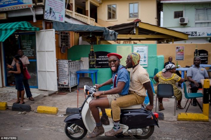 El estilista ghanés Daniel Quist (conduciendo la scooter) y el pionero de la moda DJ Evans Mireku Kissi - más conocido como Steloo-, por las calles de Accra. and Kissi go for a spin around Accra, much to the surprise of some onlookers 