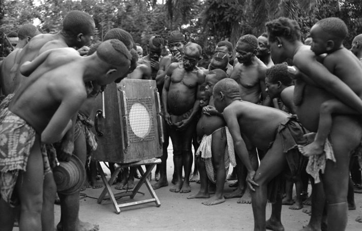 Pigmeos Batwa del Congo escuchan las grabaciones de sus canciones que les ha hecho el etnomusicólogo sudafricano Hugh Tracey, en 1958. Imagen de la International Library of African Music (ILAM).